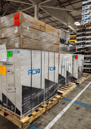 ACiQ HVAC units stacked on pallets inside a warehouse, showing available inventory for contractors.