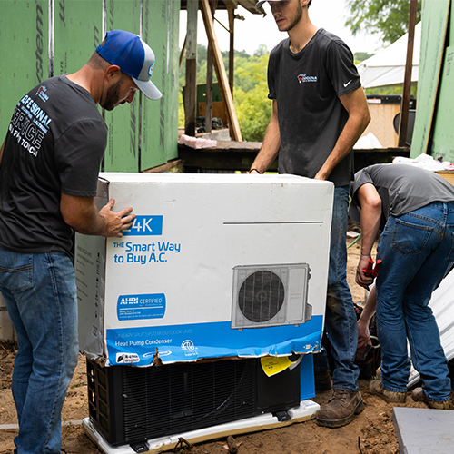 HVAC technicians installing ACiQ heat pump condenser at residential job site
