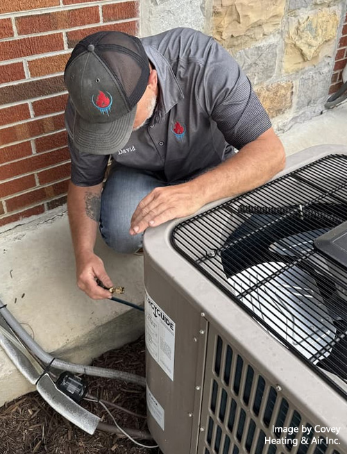 David Covey performing maintenance on an outdoor air conditioning unit.