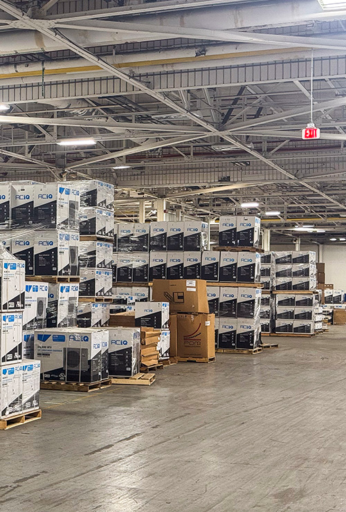 Rows of palletized ACiQ HVAC equipment stocked inside a warehouse.