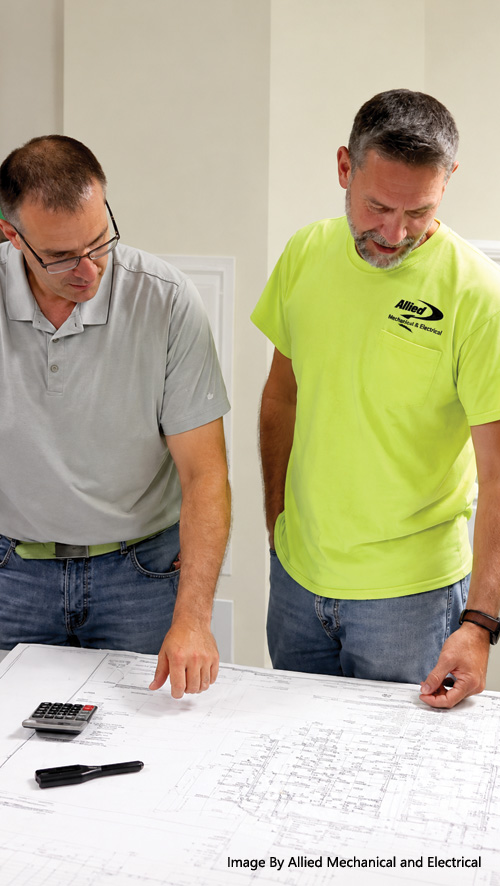 Allied Mechanical & Electrical team members reviewing commercial construction blueprints