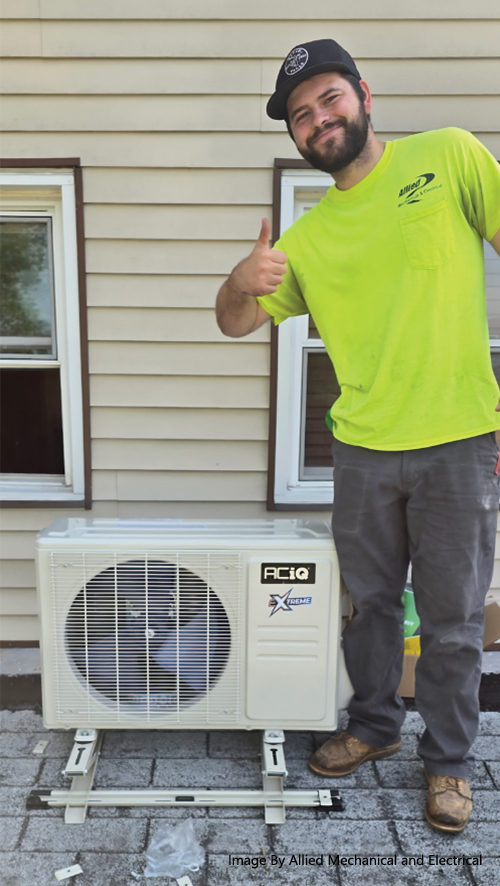Allied Mechanical & Electrical technician giving a thumbs up next to an ACiQ Extreme mini split outdoor unit