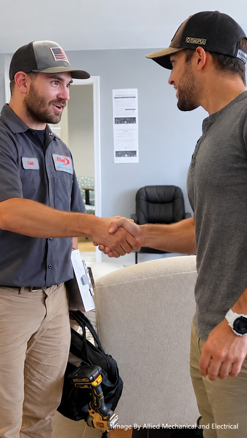 Allied Mechanical & Electrical service technician shaking hands with a homeowner