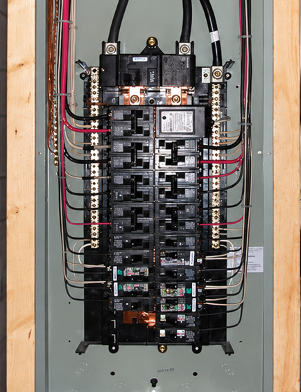 Open residential electrical panel showing multiple circuit breakers, wiring, and electrical connections
